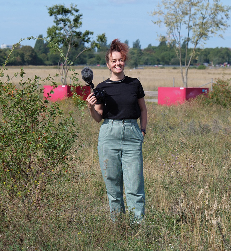 Maud Dieminger with microphone in a meadow